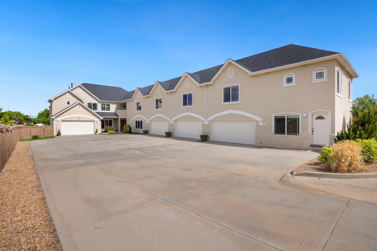 A modern suburban residential building featuring a large driveway under a clear blue sky.